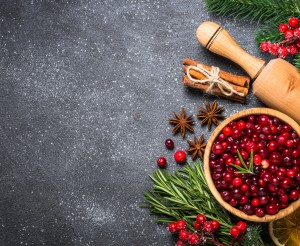 Christmas food baking background. Cranberry, orange, sugar, spices on black stone background. Top view copy space.