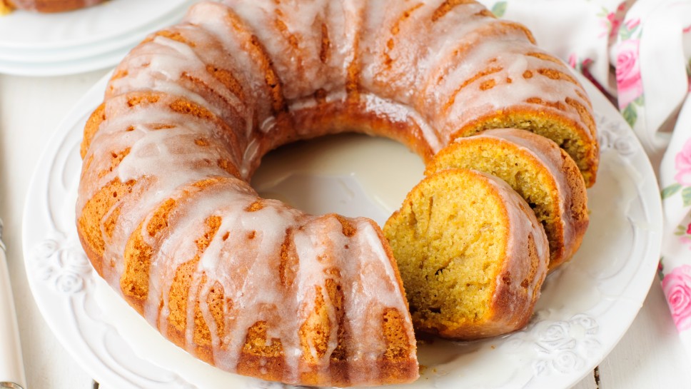 Sliced Pumpkin Bundt Cake with Sugar Icing on a White Plate